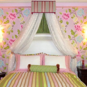 Cleveland Interior Design - Princess Bedroom. Drapery above an upholstered headboard flanked by gold wall sconces. Floral wallpaper accent wall.